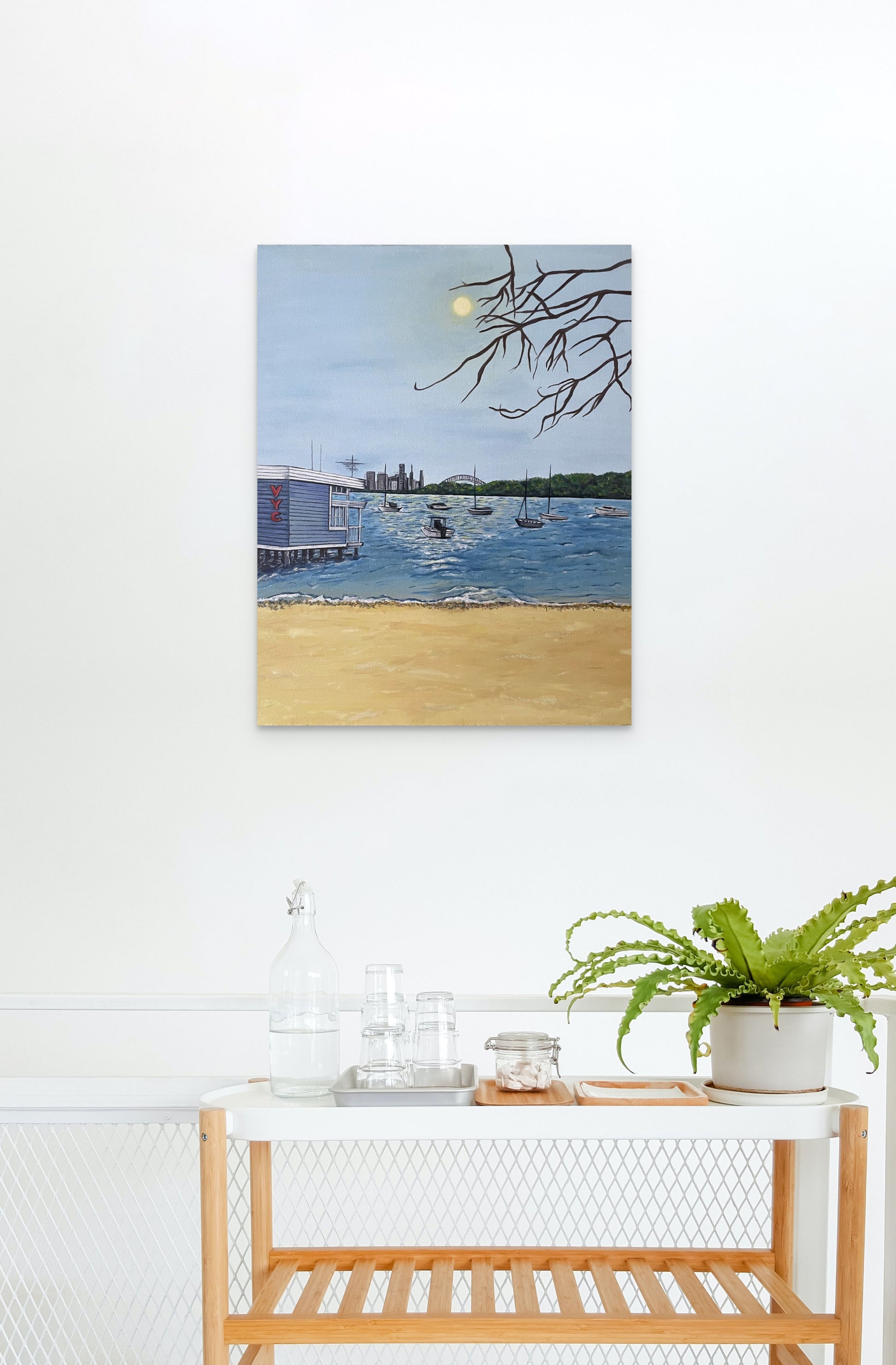 Framed painting of the Watson's Bay harbour hangs in an aesthetic beach house.