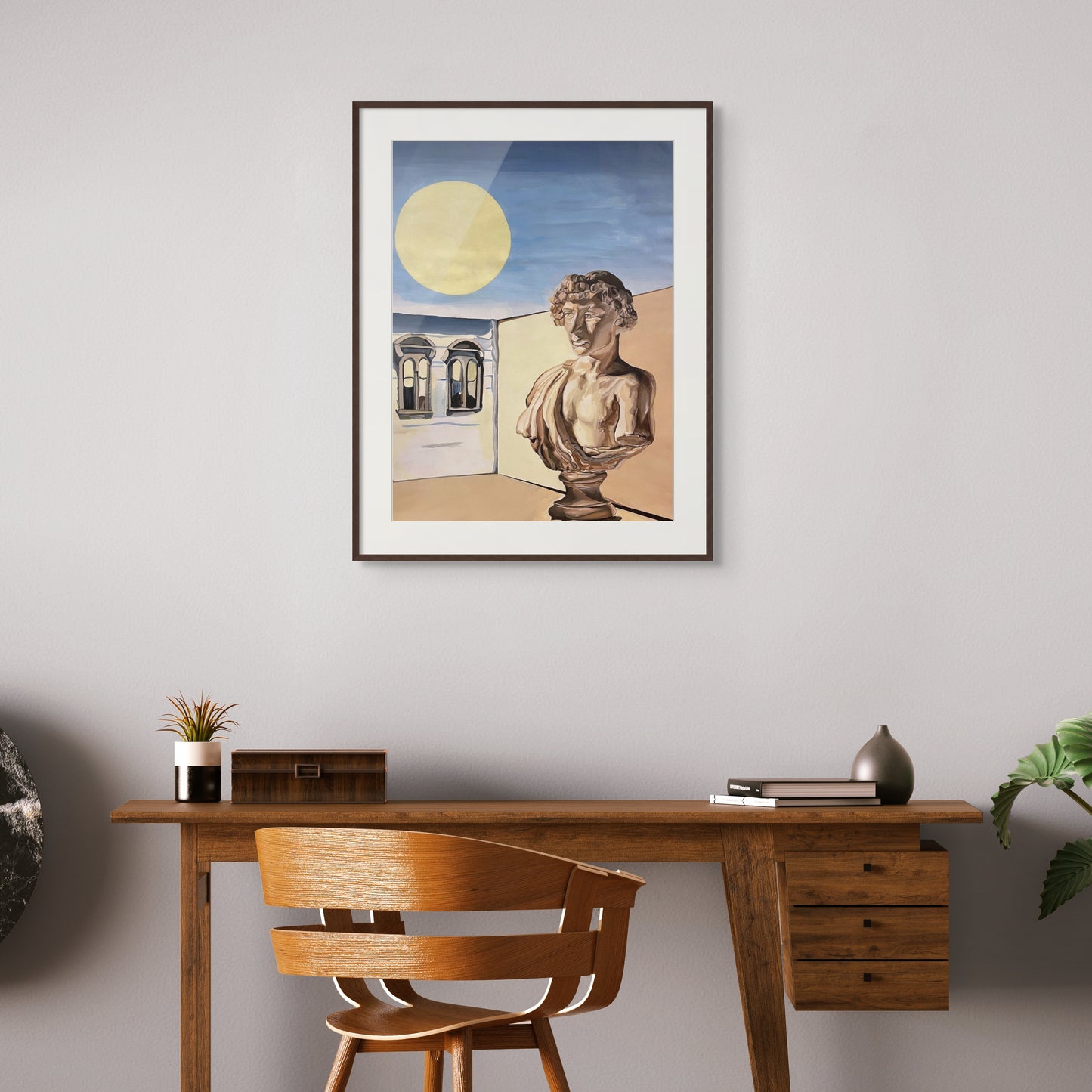 A framed painting of a roman bust hangs above a wooden desk.