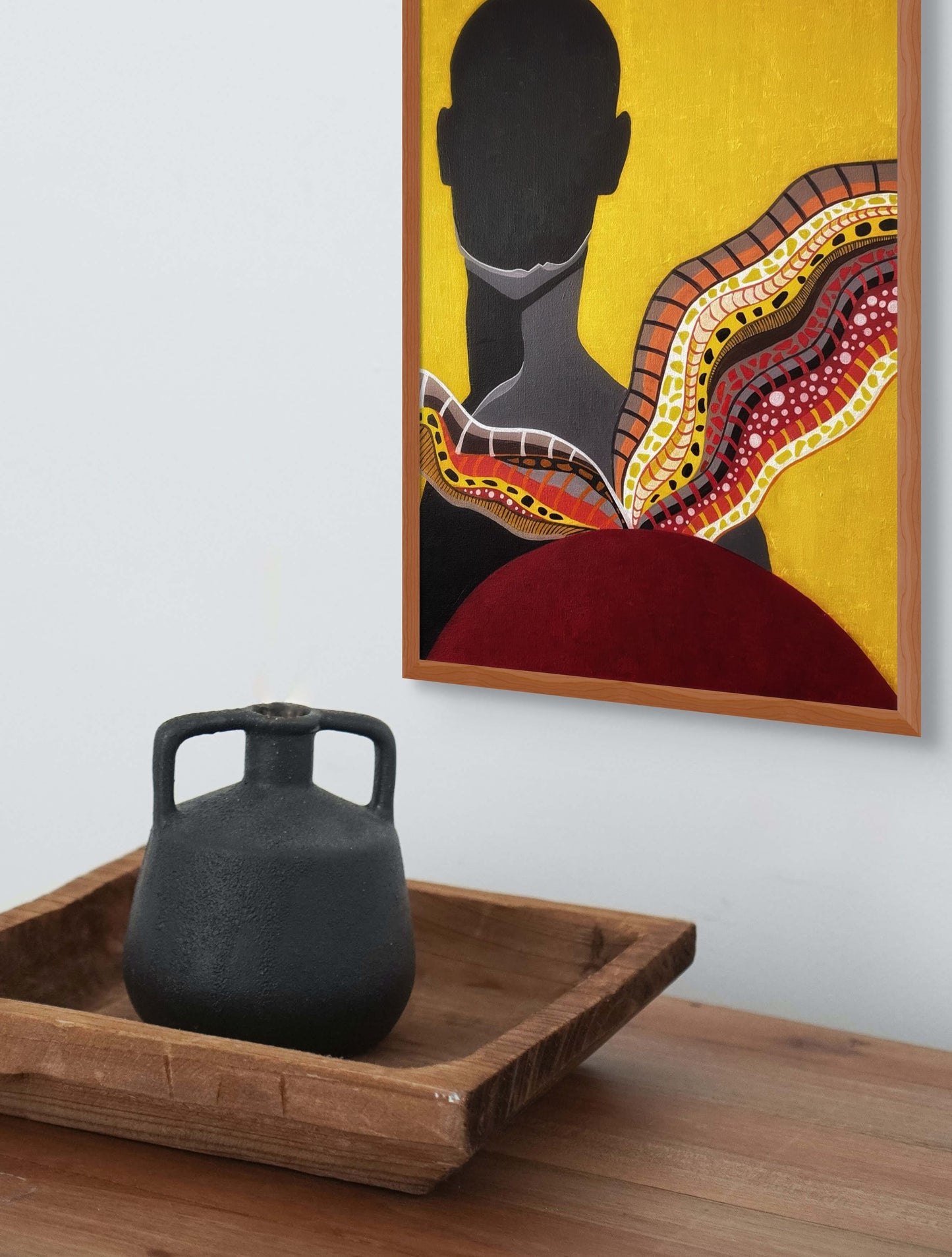 Framed of black silhouette set against a vibrant yellow backdrop, hanging above a shelf with an ancient looking jug. 