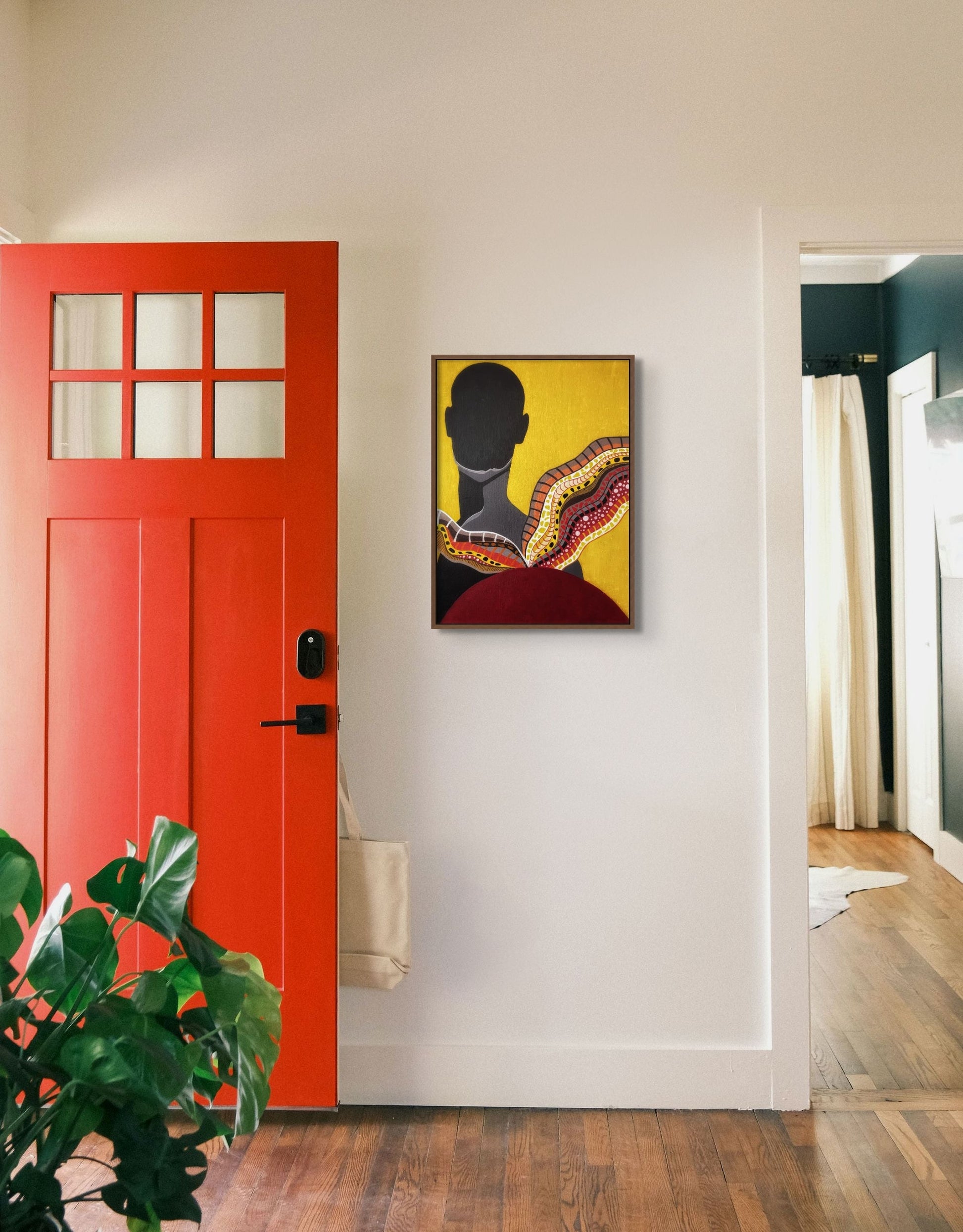 Painting of black silhouette against vibrant yellow backdrop, hanging behind a bright red door.