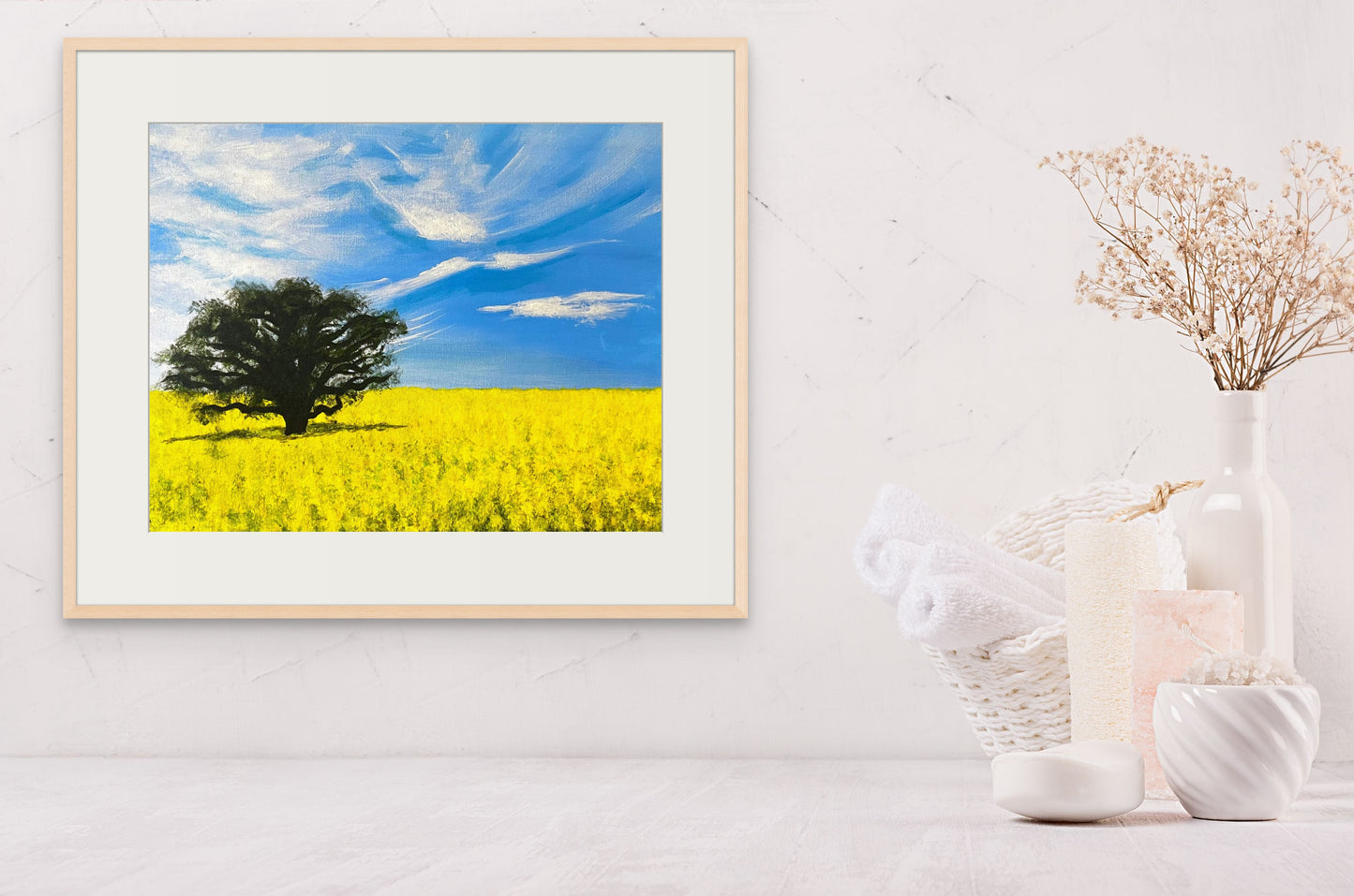 Framed painting of a canola field hanging above a bathroom vanity.