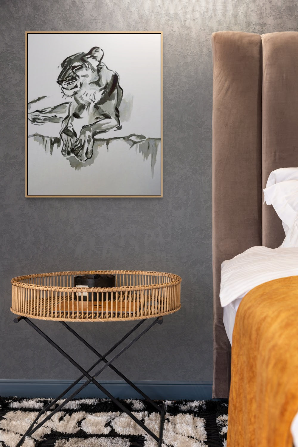 Ink painting of a lion hangs above a bedside table in a bedroom.