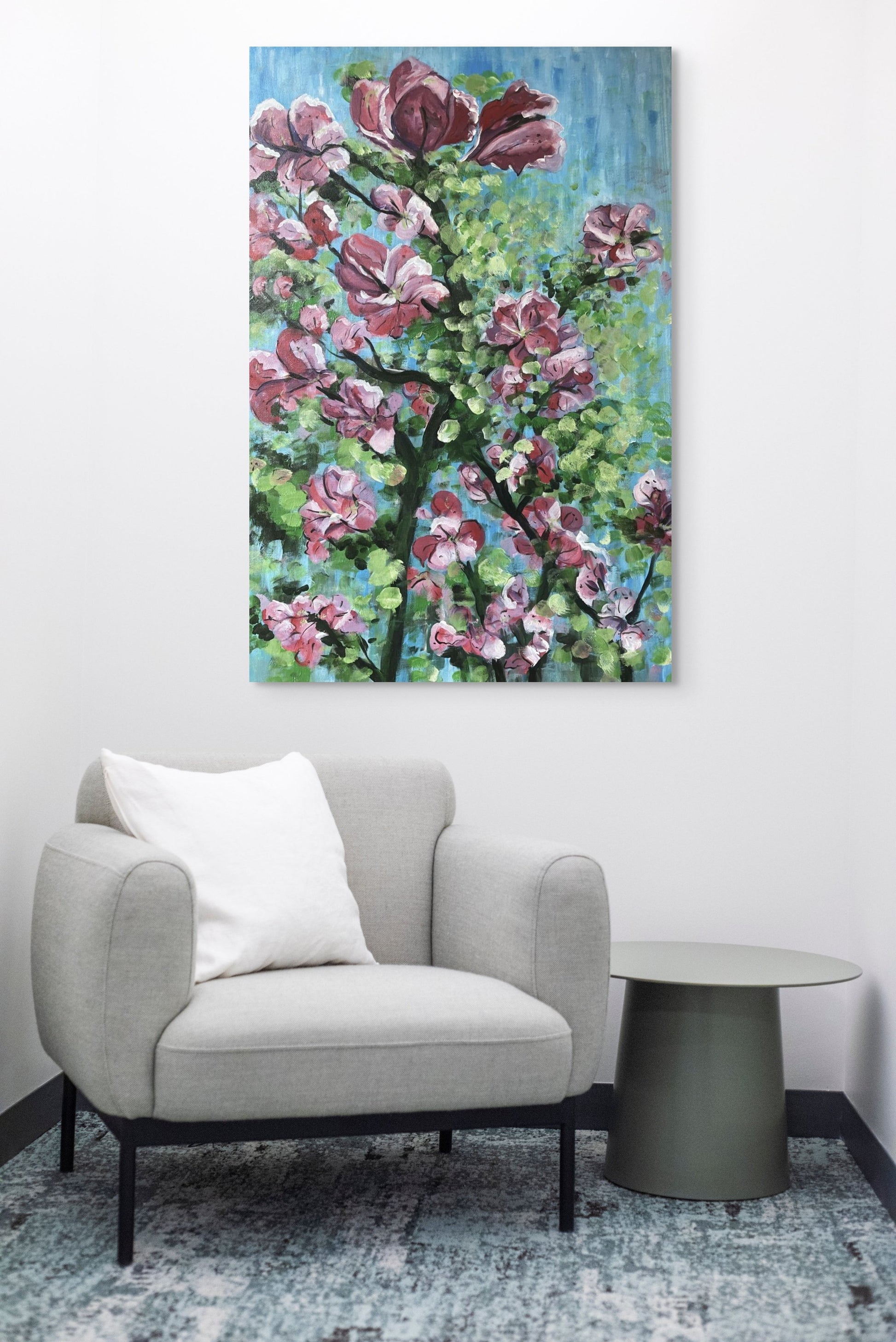 Painting of a vibrant pink bougainvillaea hanging above a grey couch.