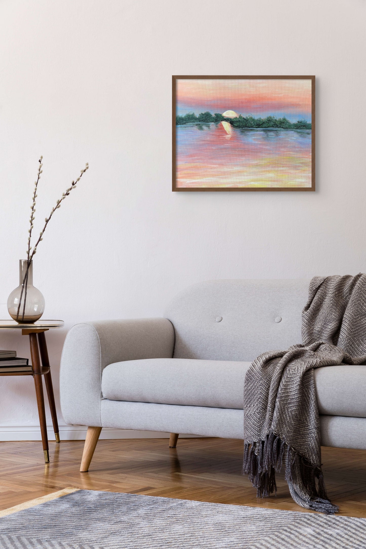 Painting of the Zambezi River at sunset hanging above a modern fabric sofa.