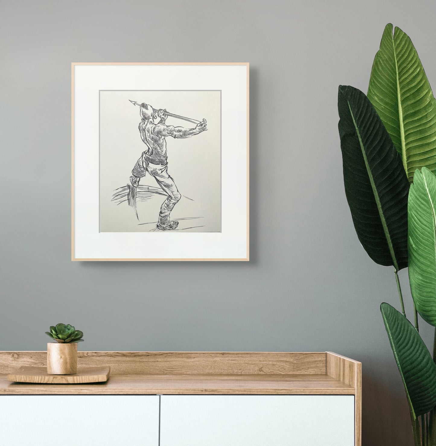 Framed pen sketch of an African warrior above a wood cabinet.