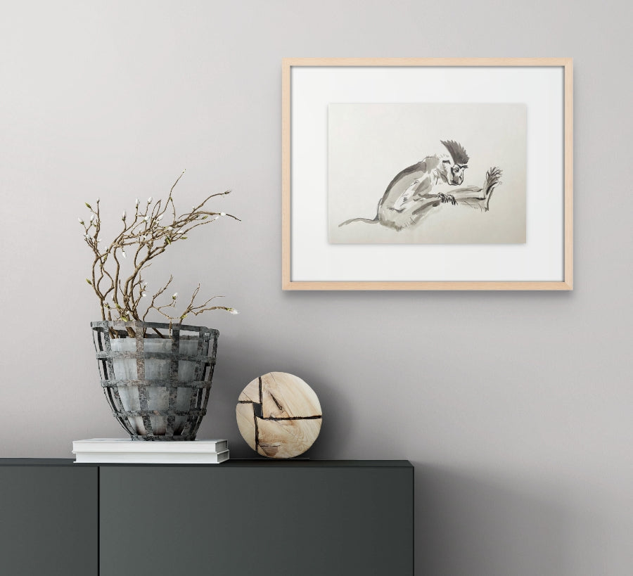 Greyscale painting of an African Vervet Monkey hanging on a light grey wall above a grey cupboard.